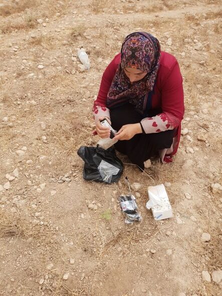 Sara Awadi collecting soil samples near an e-waste burn site